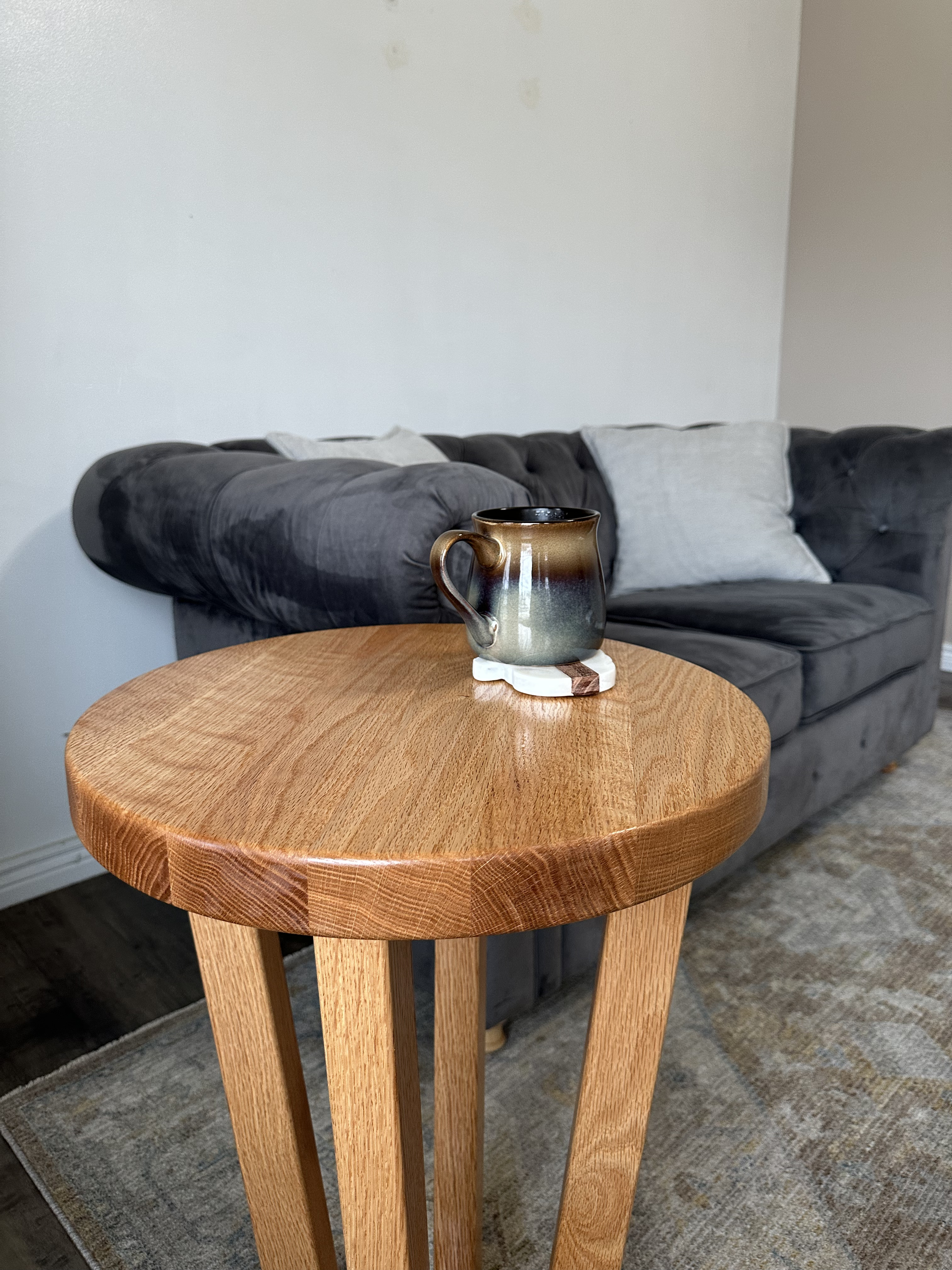 Round oak end table with tapered legs  - styled with coffee mug showing wood grain
